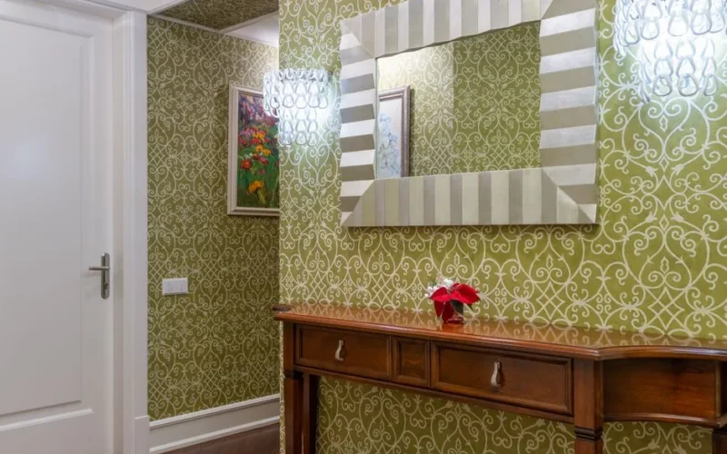 Sophisticated hallway featuring ornate wallpaper, a wooden console, and a striking decorative mirror.
