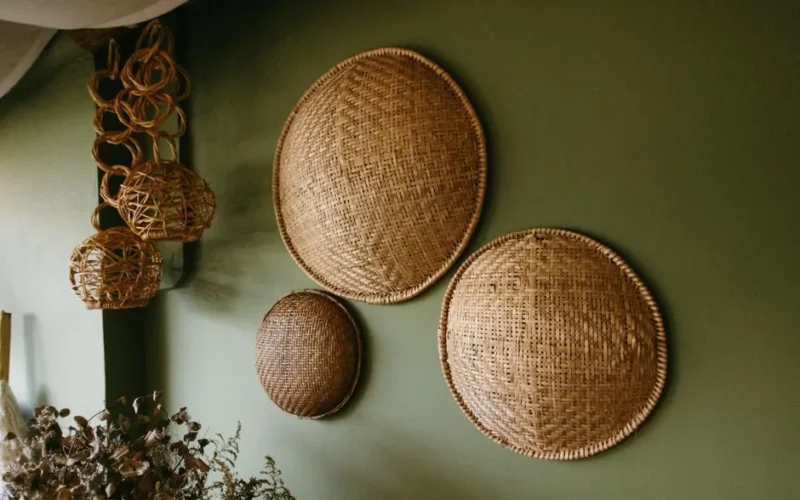 Vintage woven bamboo baskets hung on a green wall for rustic home decor.