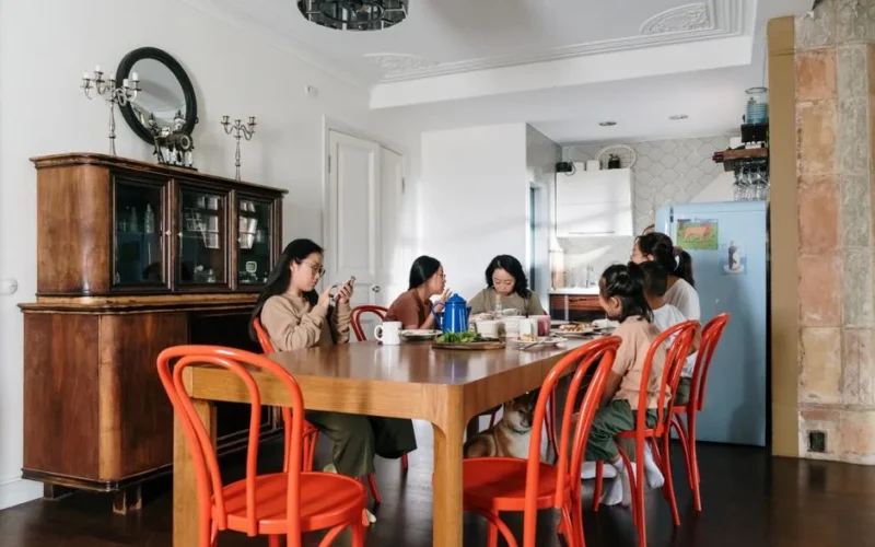 A happy family enjoying breakfast together in a contemporary dining room with wooden furniture and red chairs.