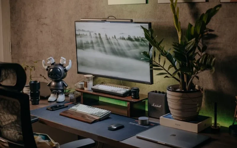 Stylish home office setup with tech gadgets, large monitor, and modern decor.