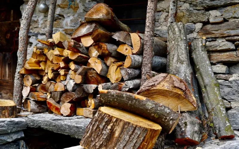 A stack of chopped firewood against a rustic stone wall, embodying a cozy autumn feel.