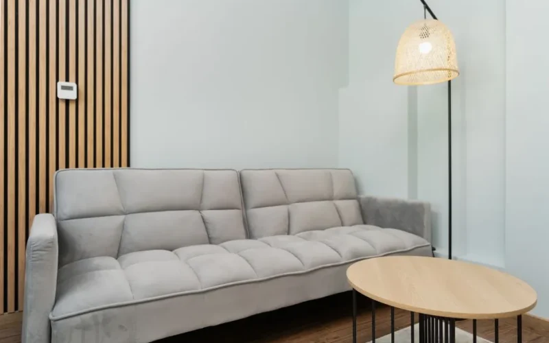 Contemporary living room featuring a grey sofa, wooden accents, and a woven lamp for a minimalist look.