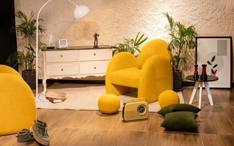 Warm living room setup with yellow chair, vintage radio, plants, and chic decor creating a cozy atmosphere.