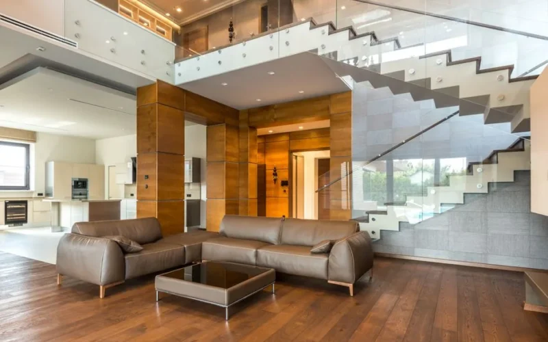 Spacious modern living room with leather sofas and a glass staircase, showcasing luxury interior design.