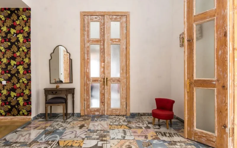 Charming vintage room with distressed wooden doors and graphic patterned floor.