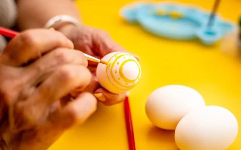 Close-up of hands painting Easter eggs with bright colors, creative and festive.