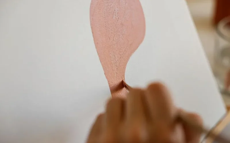 A close-up shot of a hand painting abstract art on a blank canvas.