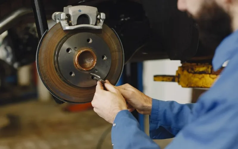 Mechanic working on brake disc in an auto repair workshop, close-up, focus on hands.