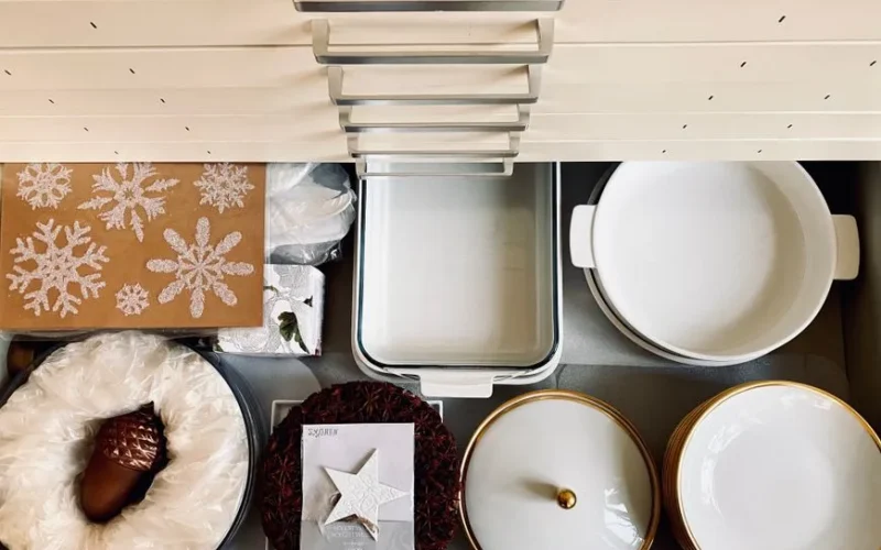 Top view of a kitchen drawer organized with dishes and holiday decorations, creating a neat and festive presentation.