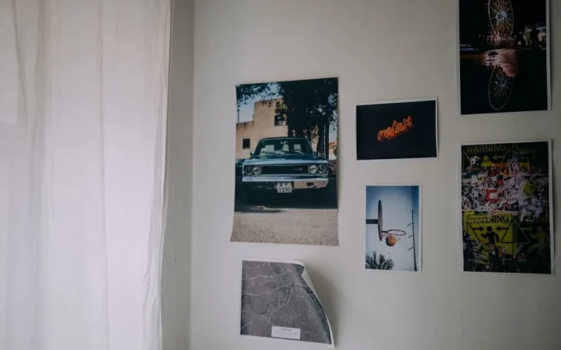 A collection of posters and photographs on a white wall, creating an artistic ambiance.