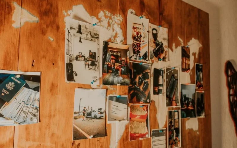 A collection of travel photos pinned on a wooden map-themed wall, evoking adventure and nostalgia.