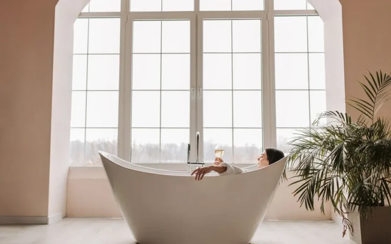 A serene scene of a woman enjoying a glass of wine while relaxing in a modern bathtub indoors.