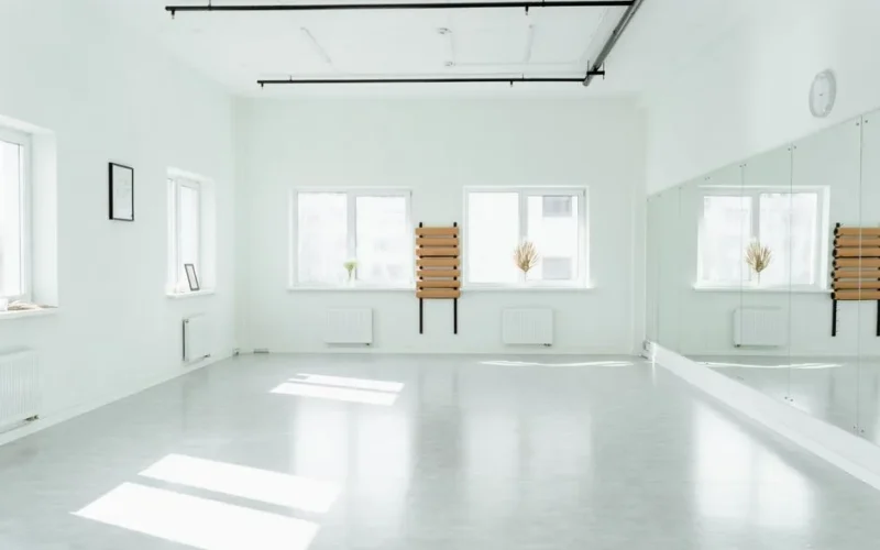 Bright and empty dance studio with mirrors and sunlight streaming in.