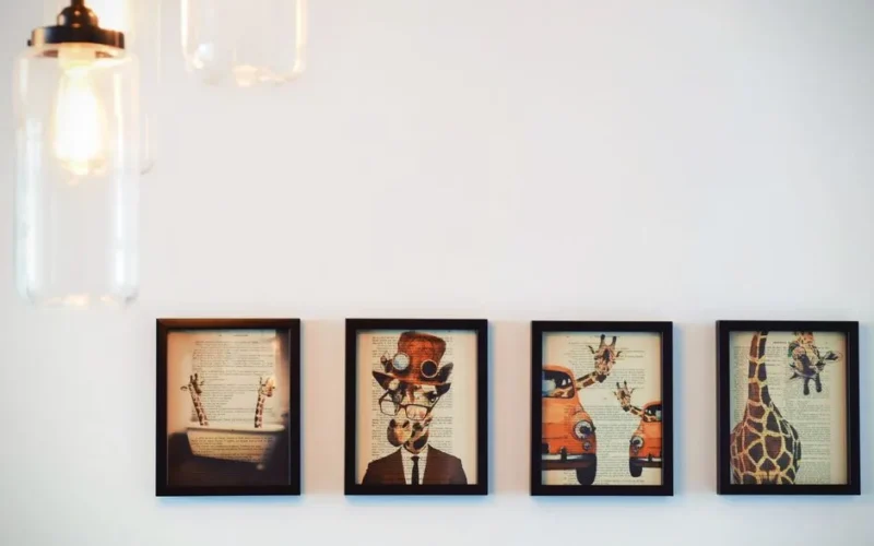 A modern interior display of four framed giraffe-themed artworks, enhanced by warm lighting.