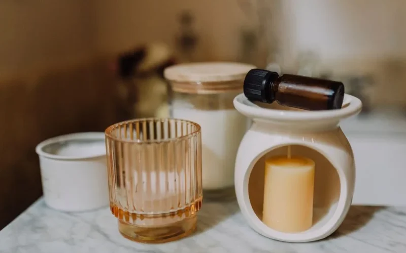 A serene aromatherapy arrangement with candles, glass jars, and essential oil on marble.