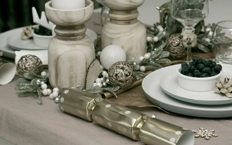A beautifully decorated Christmas table with candles, ornaments, and festive tableware.