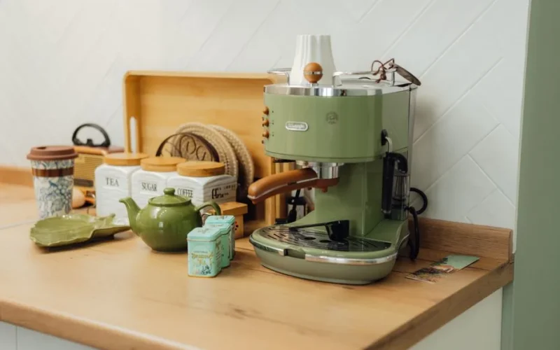 Chic kitchen setup with a green espresso machine and tea setup on a wooden counter.