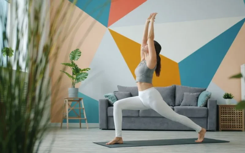 Woman doing yoga in a modern living room with colorful abstract wall.