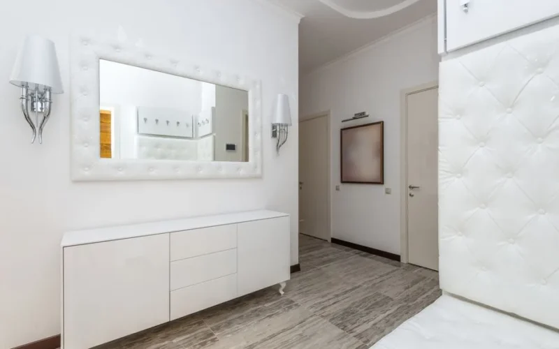 Stylish modern interior featuring white decor, a large wall mirror, and contemporary furnishings.