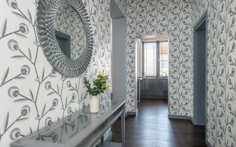 Contemporary hallway featuring decorative wallpaper, a mirror, and a table with flowers, creating an elegant atmosphere.