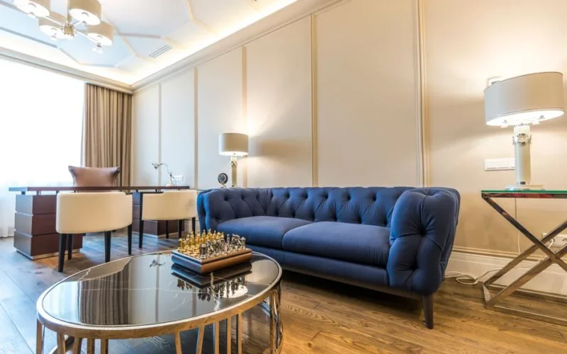 Bright modern living room featuring a blue couch, elegant decor, and ample natural light.