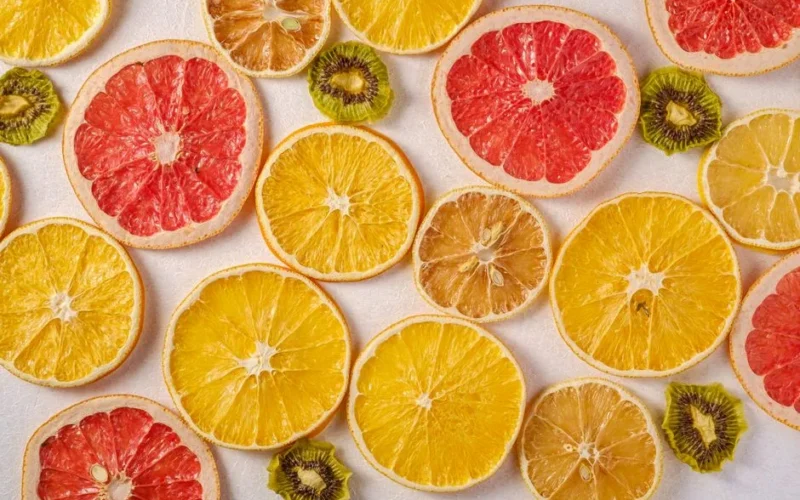 Vibrant arrangement of dried slices of citrus fruits with kiwi on a white background.