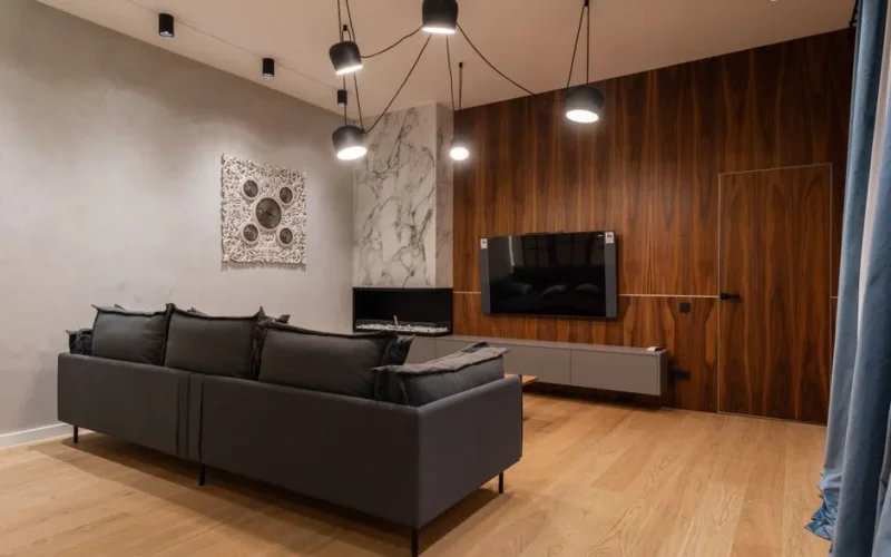 Modern TV hanging on wooden wall in front of comfortable couch in spacious stylish living room