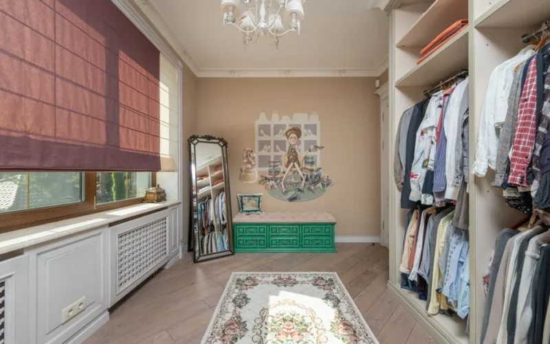 Elegant walk-in closet with clothes, chandelier, and a full-length mirror.