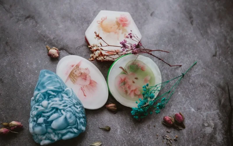 Top view of creative aromatic handmade soaps arranged on gray surface with colorful dried flowers and herbs