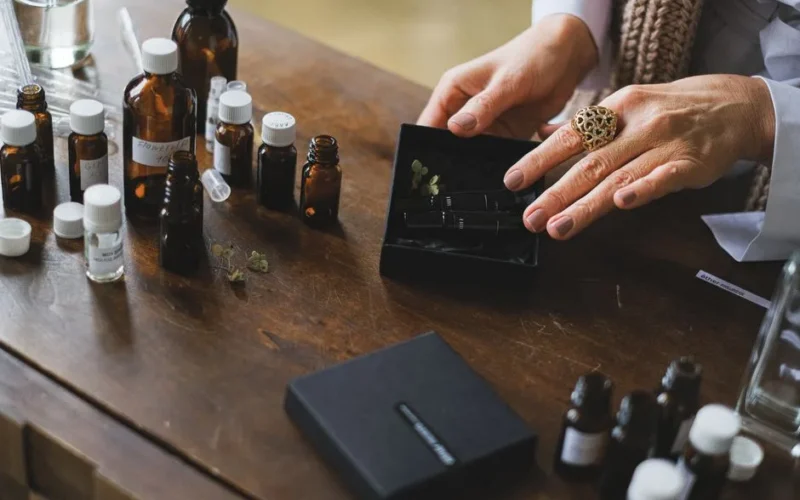Hands sorting essential oil bottles on a wooden table, highlighting aromatherapy and natural wellness.