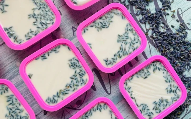 Top view of handmade lavender soap bars in pink molds with dried lavender sprinkles.