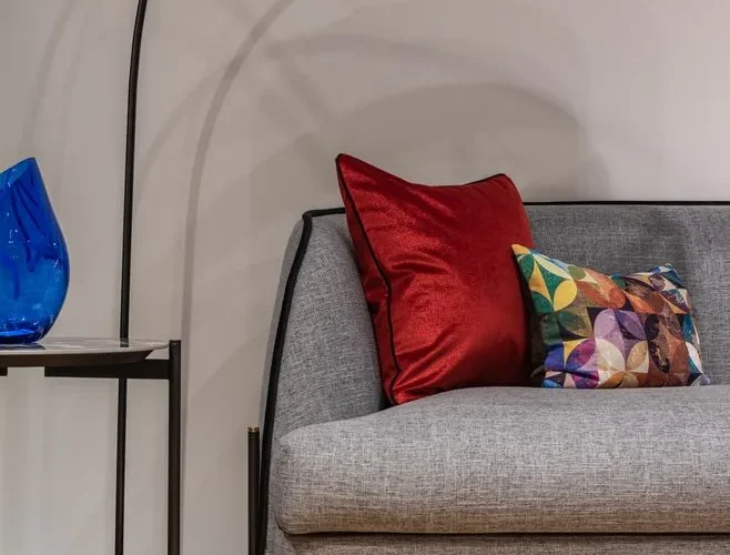 Comfortable gray couch with colorful cushions placed at wall near small side table in modern living room of contemporary apartment