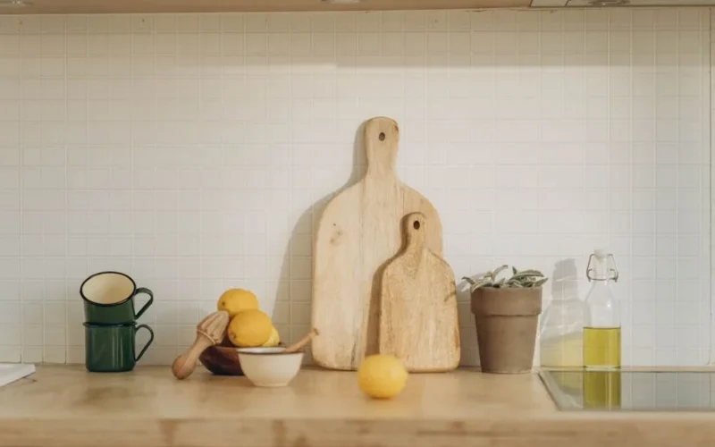 Warm kitchen scene featuring cutting boards, lemons, and cups on a wooden counter.