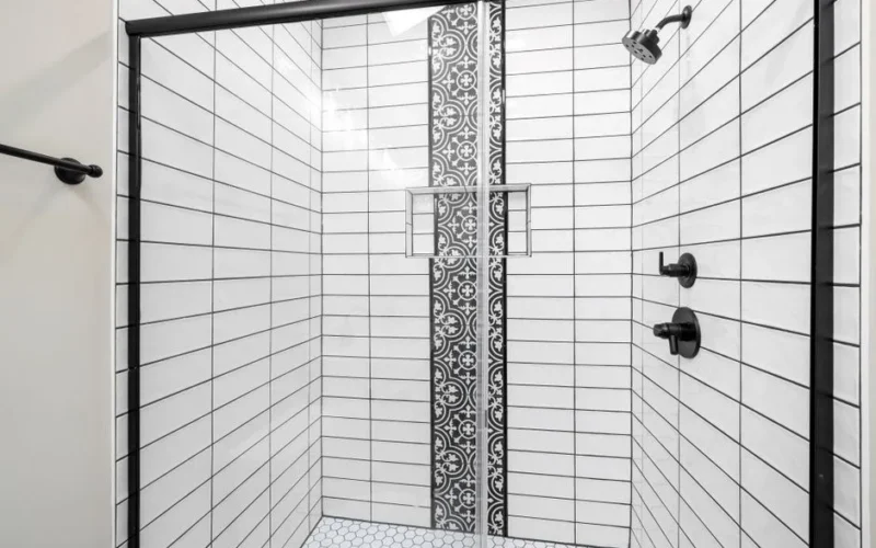 Stylish shower with white subway tiles and a striking black patterned accent wall for a modern touch.