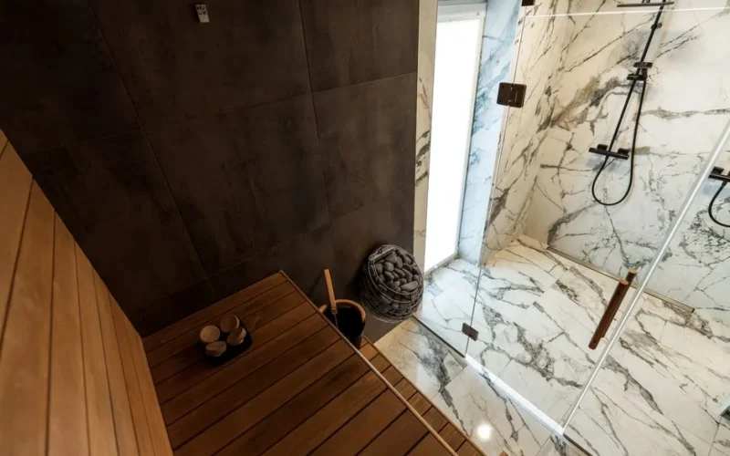 A contemporary sauna with a sleek design and adjacent marble shower, showcasing luxury indoor architecture.