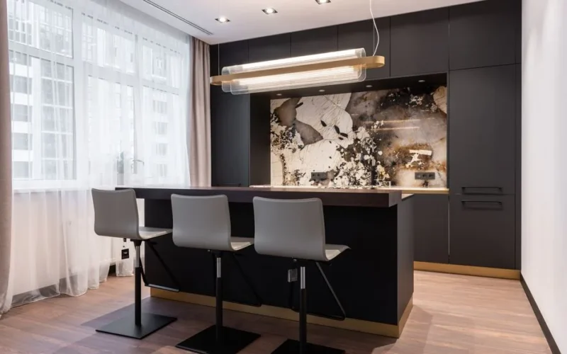 Interior of contemporary kitchen with marble panel over cooking zone and bar counter with chairs
