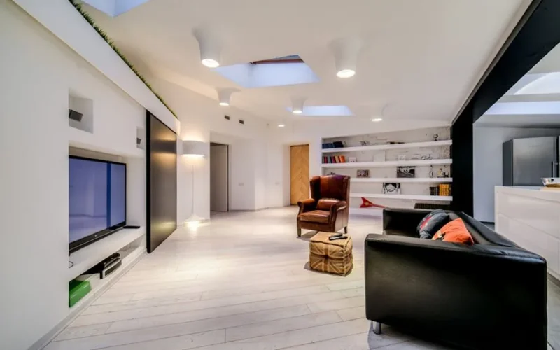 Spacious modern living room featuring a sleek design with furniture and skylights.