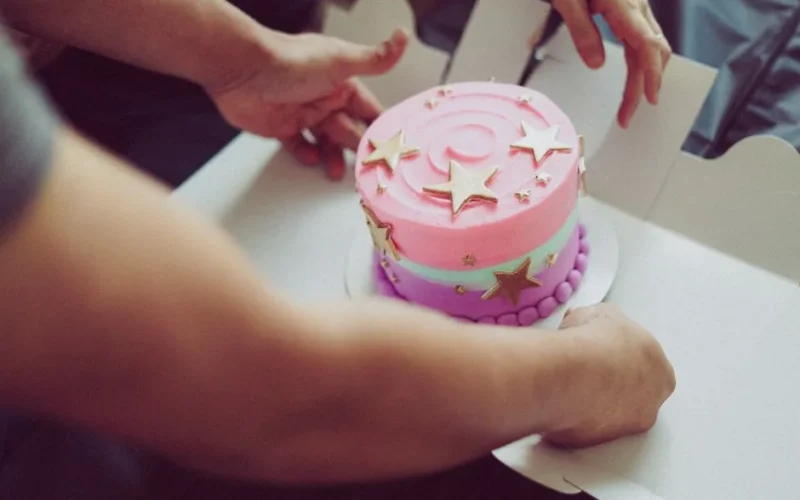 Close-up of a vibrant birthday cake with star decorations being placed in a box.