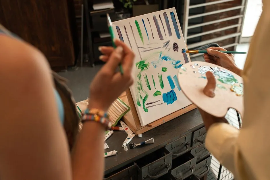 Two artists painting an abstract artwork in a studio, sharing creative techniques.