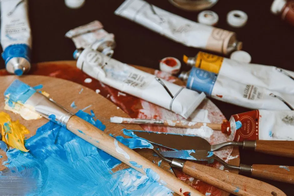 A close-up of a colorful artist's palette with paintbrushes and paint tubes, vibrant and inspiring.