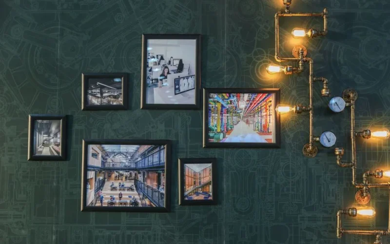 Industrial style wall art with vintage pipe lighting on a green textured wall adds a unique touch.