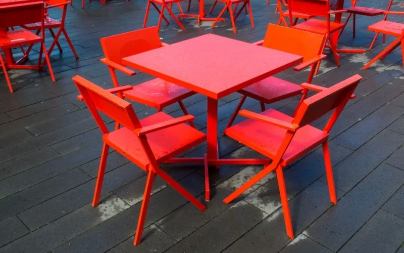 Vibrant red chairs and tables on a terrace with a wooden floor at Bergen aan Zee.