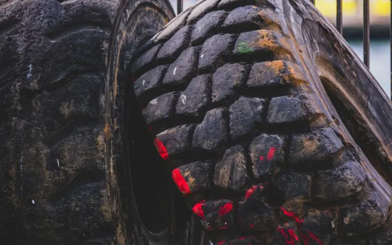 Detailed view of old, worn truck tires with visible red paint marks in an outdoor industrial setting.