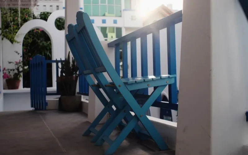 Stylish blue wooden chairs on a bright porch, perfect for relaxation and sunny ambiance.