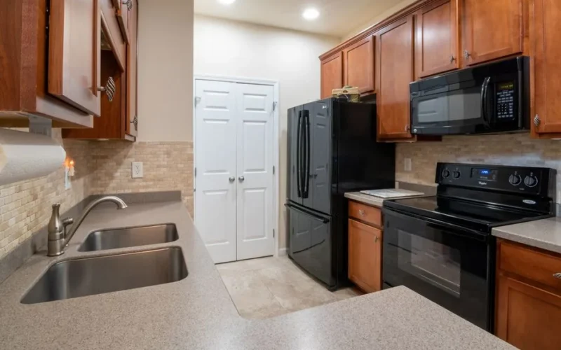 A contemporary kitchen featuring wooden cabinets, modern appliances, and a marble countertop.