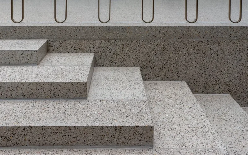 Minimalist concrete staircase featuring terrazzo texture and sleek metal railings.