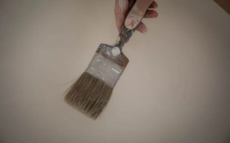 A detailed close-up of a hand holding a paintbrush with paint residue. Perfect for DIY themes.
