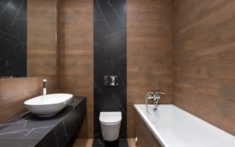 Sleek modern bathroom featuring wood paneling and marble accents, with a white basin and bathtub.