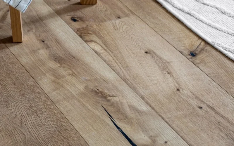 High angle view of natural wooden plank flooring next to a cozy woven rug.