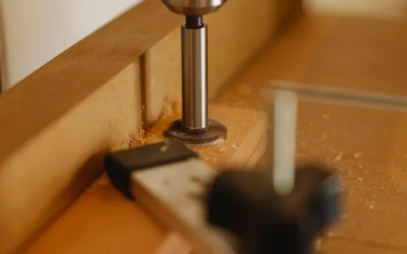 Iron part of drill machine and timber detail on workbench in modern workroom